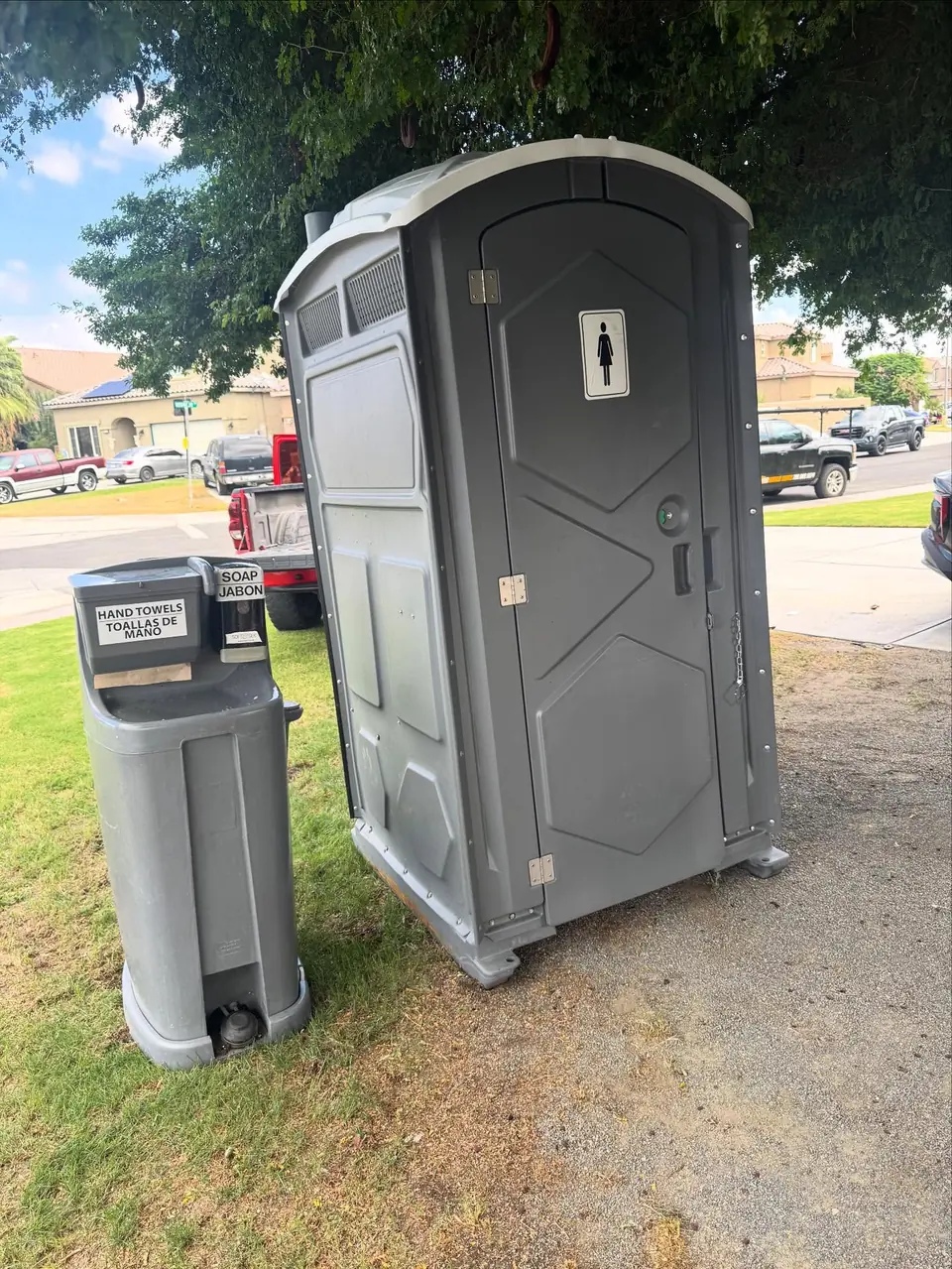 Porta potty with a handwashing station on a lawn