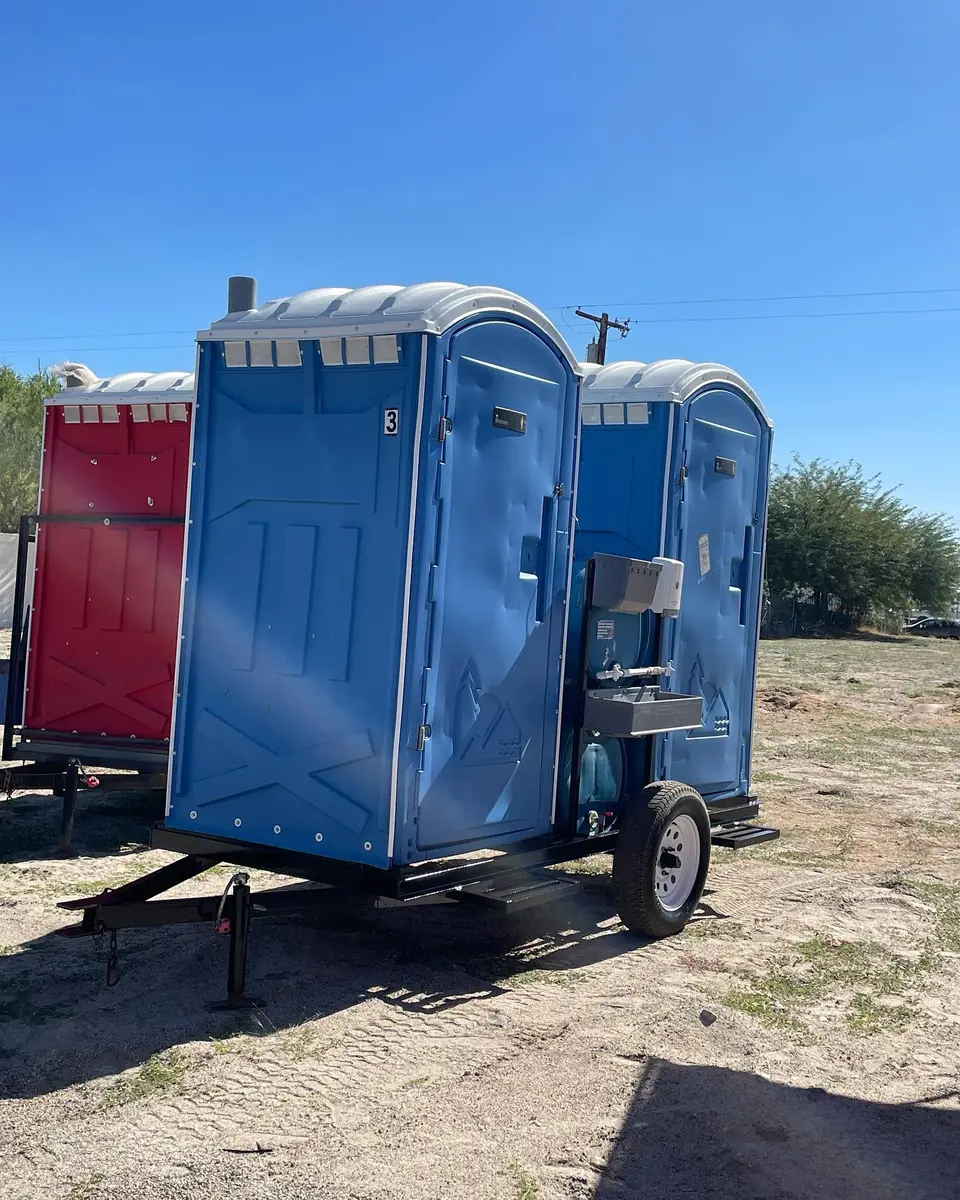 Porta potties on a towable trailer at a dirt jobsite